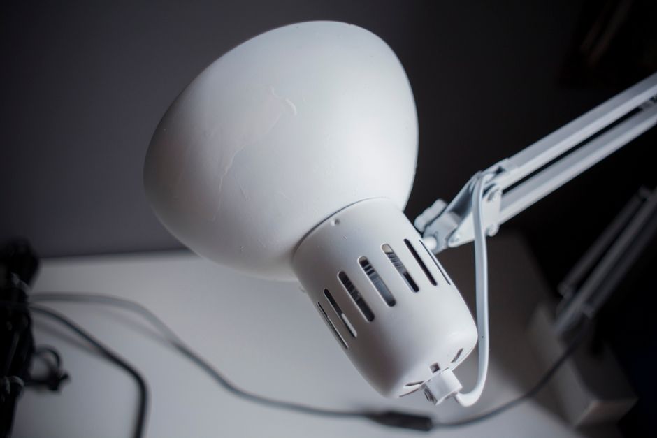 Close-up of a white desk lamp in a modern office, emphasizing its sleek design and functionality.